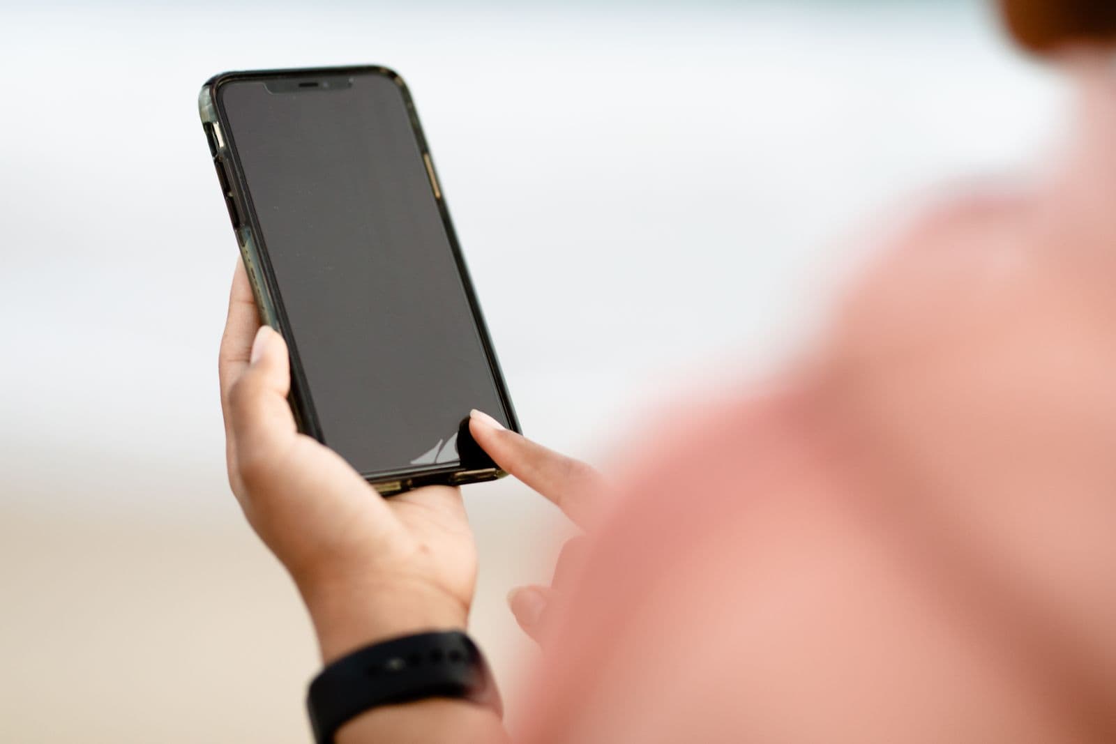 A hand holding a phone, screen dark