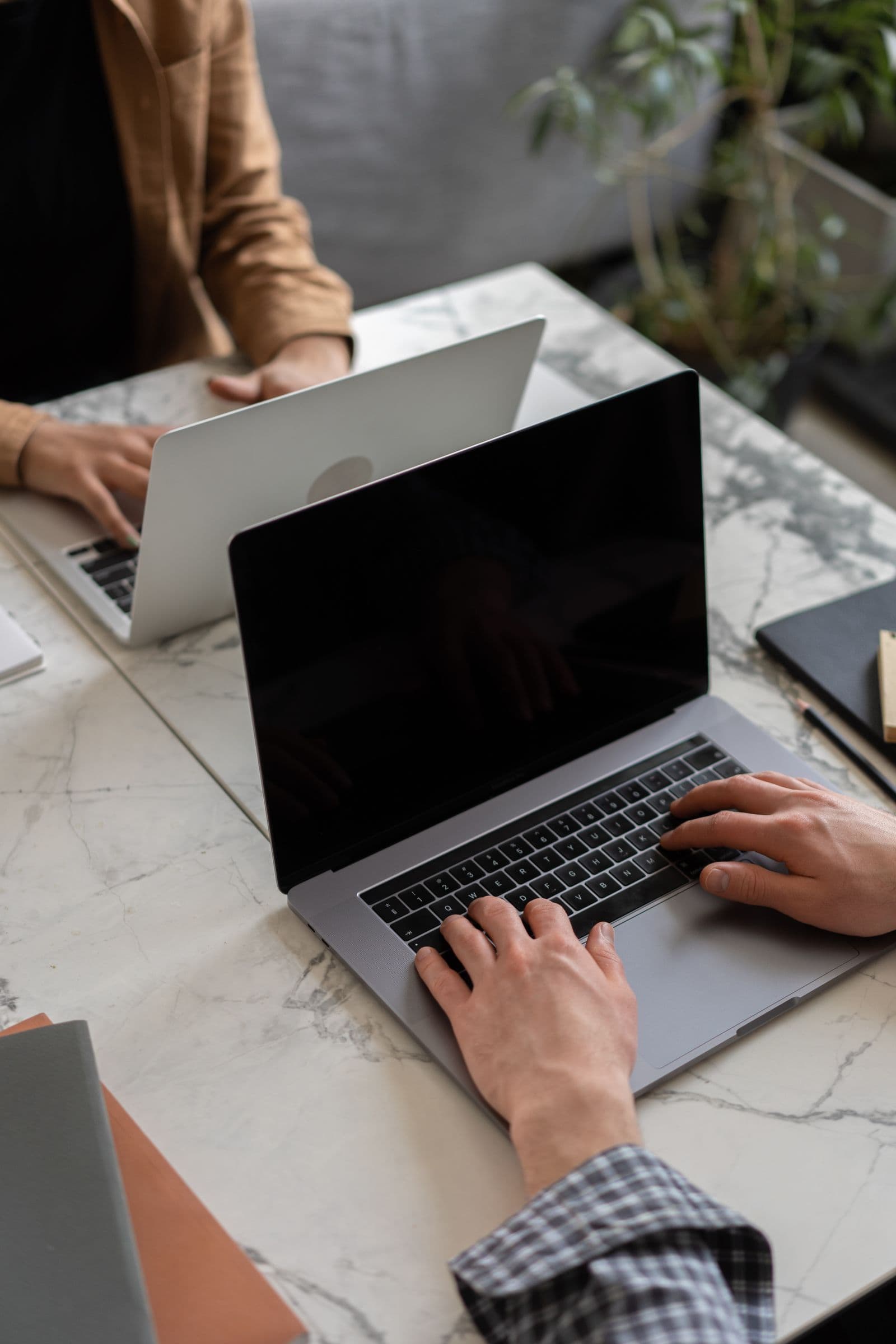 Hands typing on a laptop at a dark desk